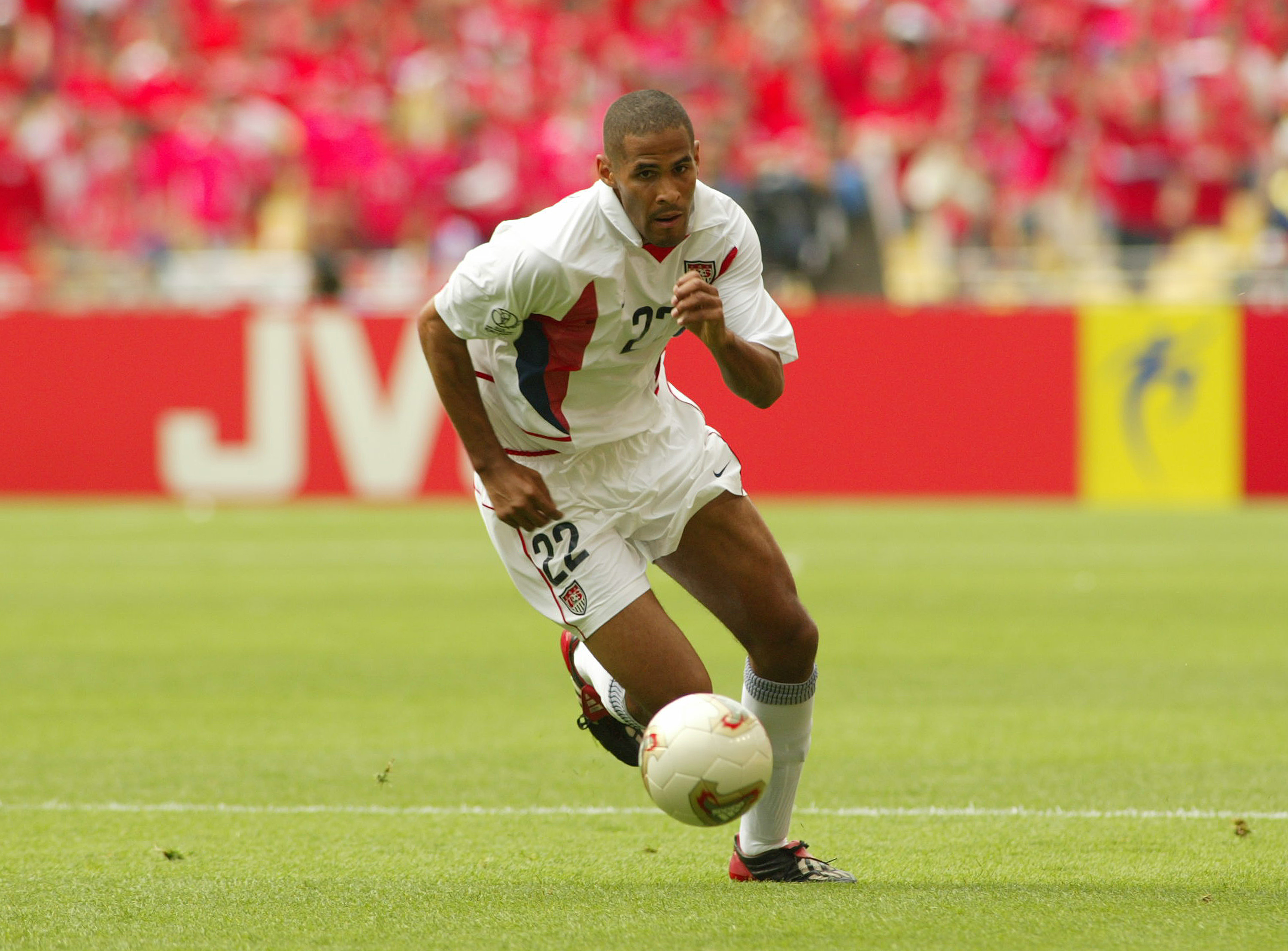 A soccer player (Tony Sanneh) playing in the white kit of the US Men's National Team.
